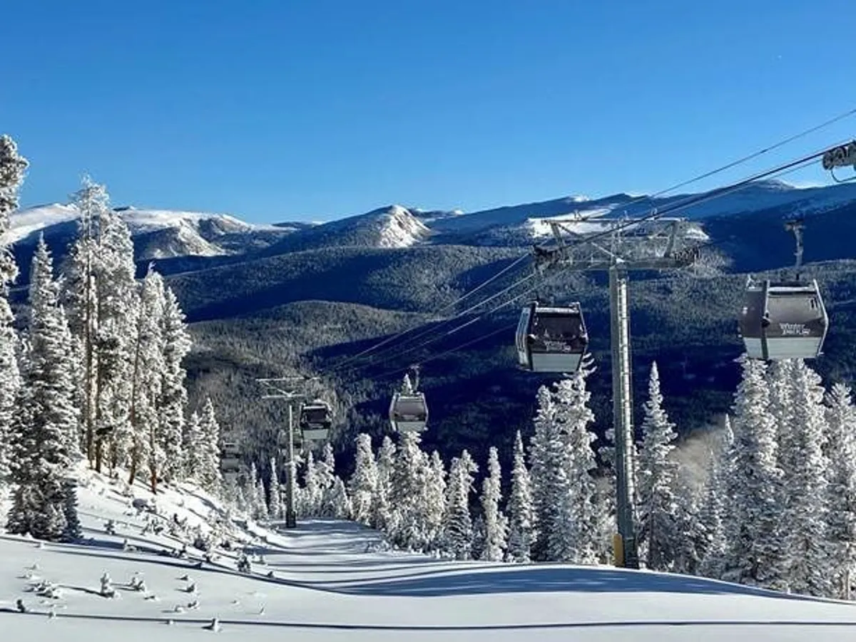 A breathtaking mountain landscape with ski lift gondolas rising above snow-covered trees and expansive mountain ranges in the background. The scene evokes a sense of adventure, tranquility, and access to world-class skiing and mountain exploration.